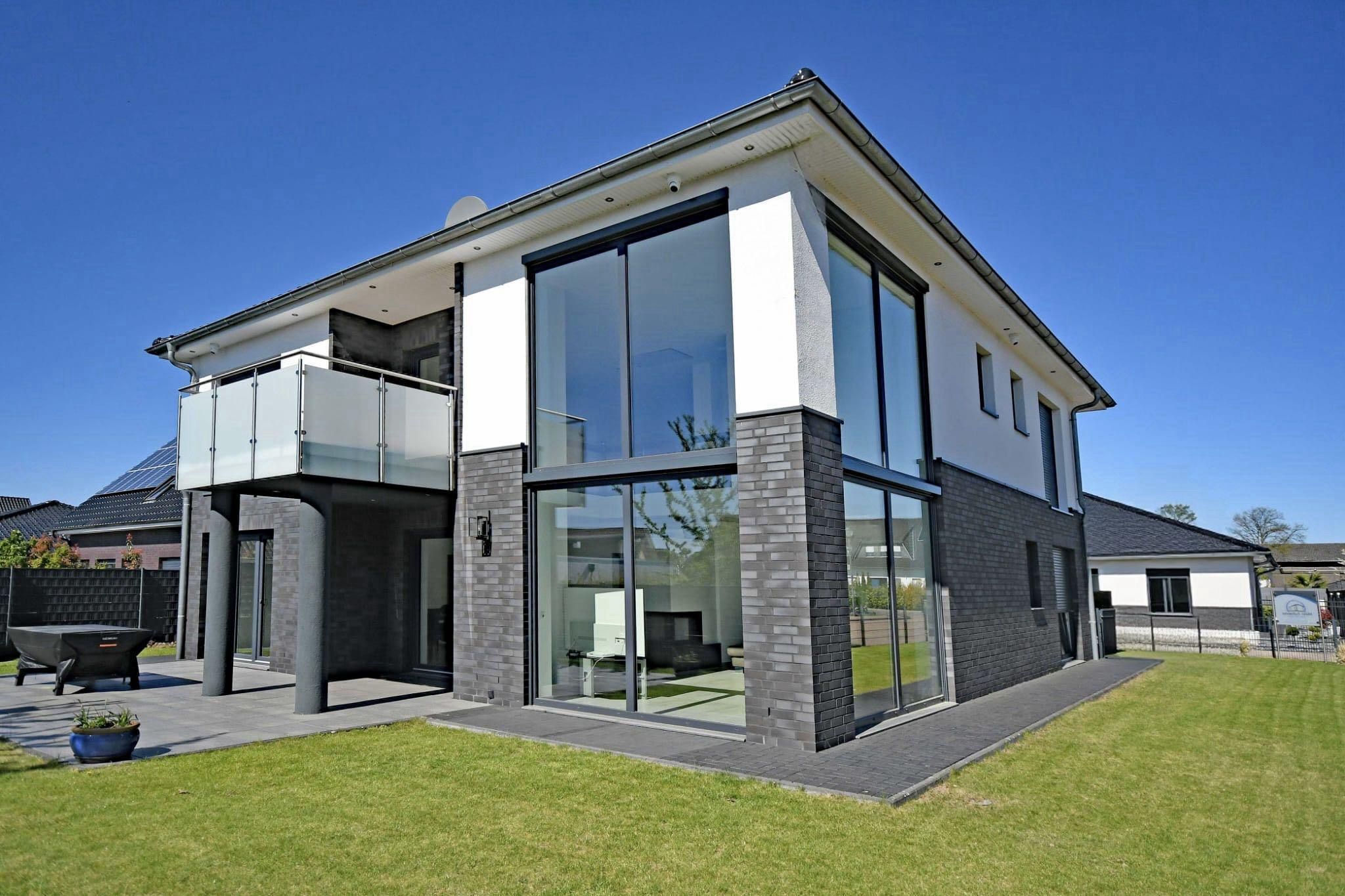Modernes Massivhaus mit weißer Fassade und grünem Rasen